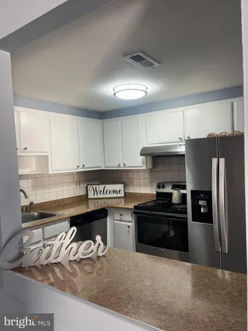 a kitchen with granite countertop a refrigerator stove and sink