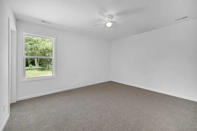 an empty room with windows and ceiling fan