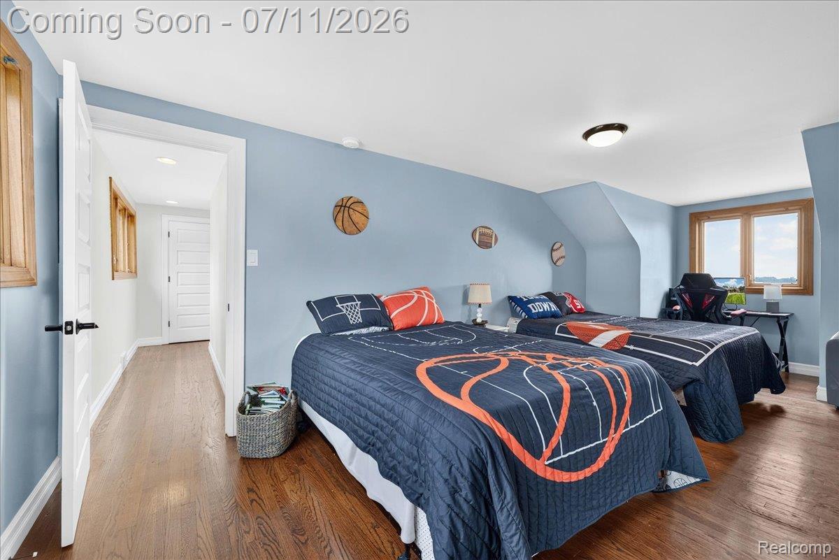 23750 East River Road Grosse Ile, MI 48138 - Photo 17 of 54 Bedroom featuring wood-finish flooring, light blue walls, and a window with wood trim