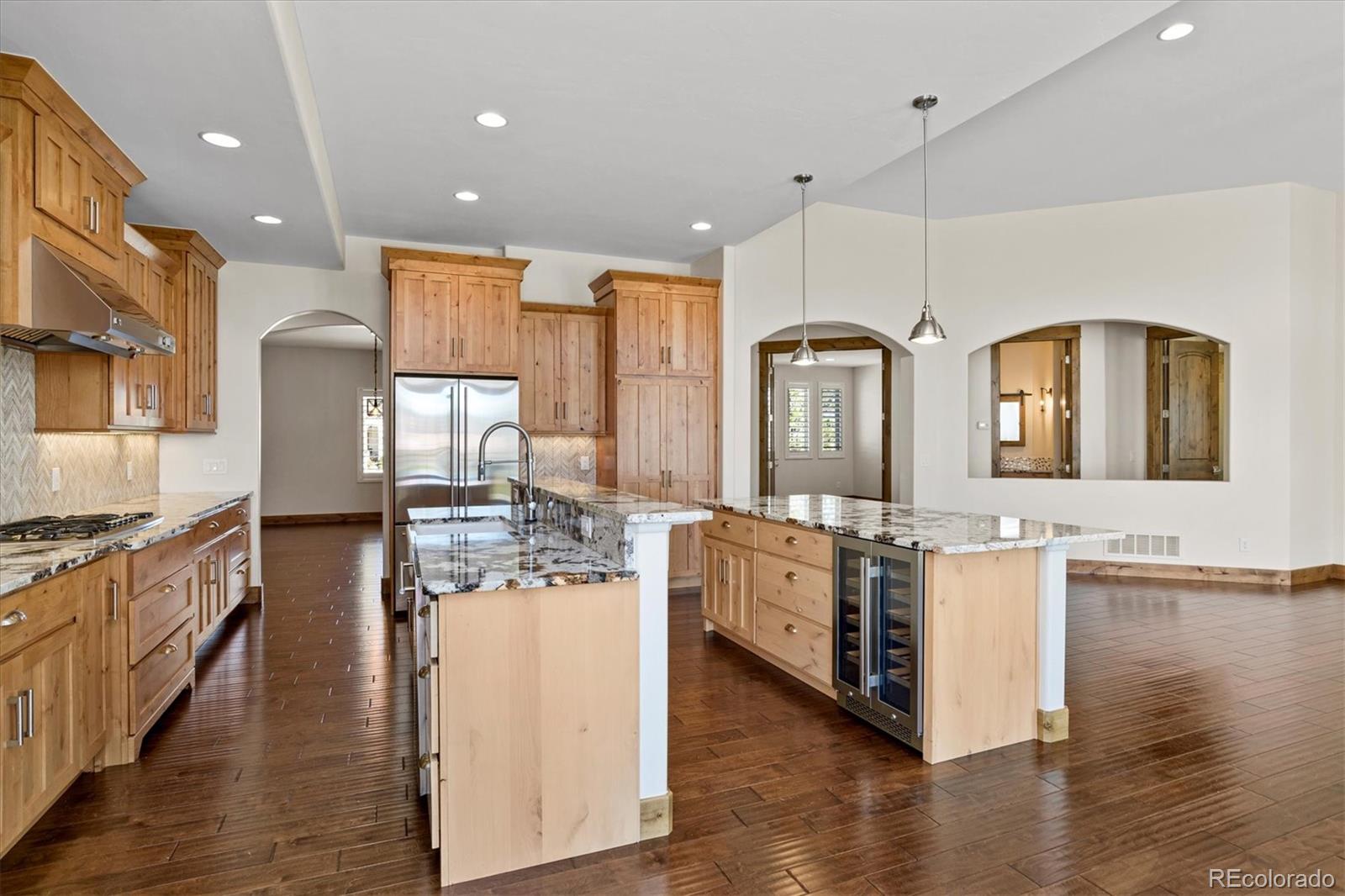 5561 Rim View Place Parker, CO 80134 - Photo 12 of 40 a kitchen with stainless steel appliances kitchen island granite countertop a stove a sink a refrigerator and white cabinets with wooden floor