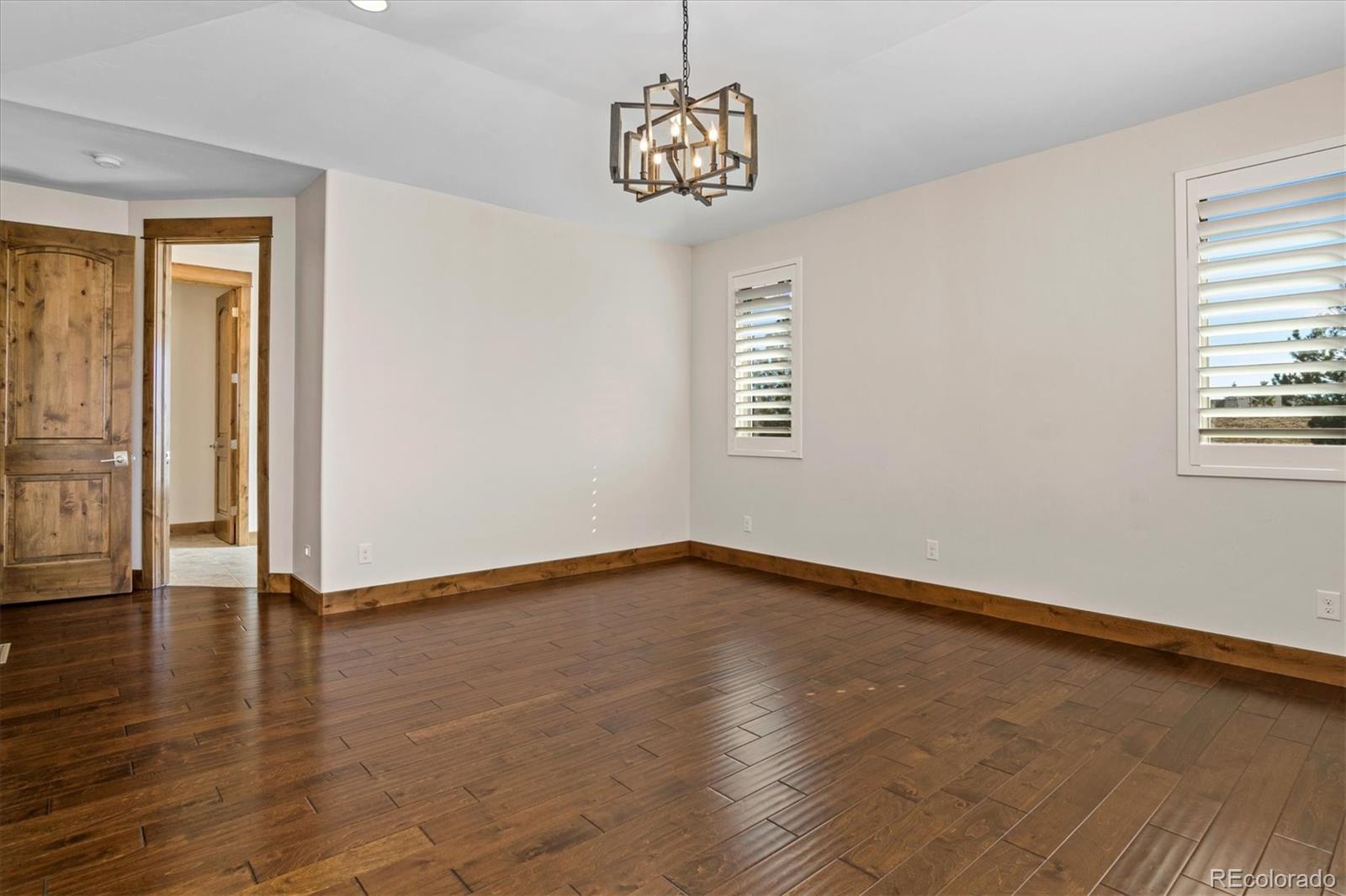 5561 Rim View Place Parker, CO 80134 - Photo 17 of 40 a view of an empty room with wooden floor and a window