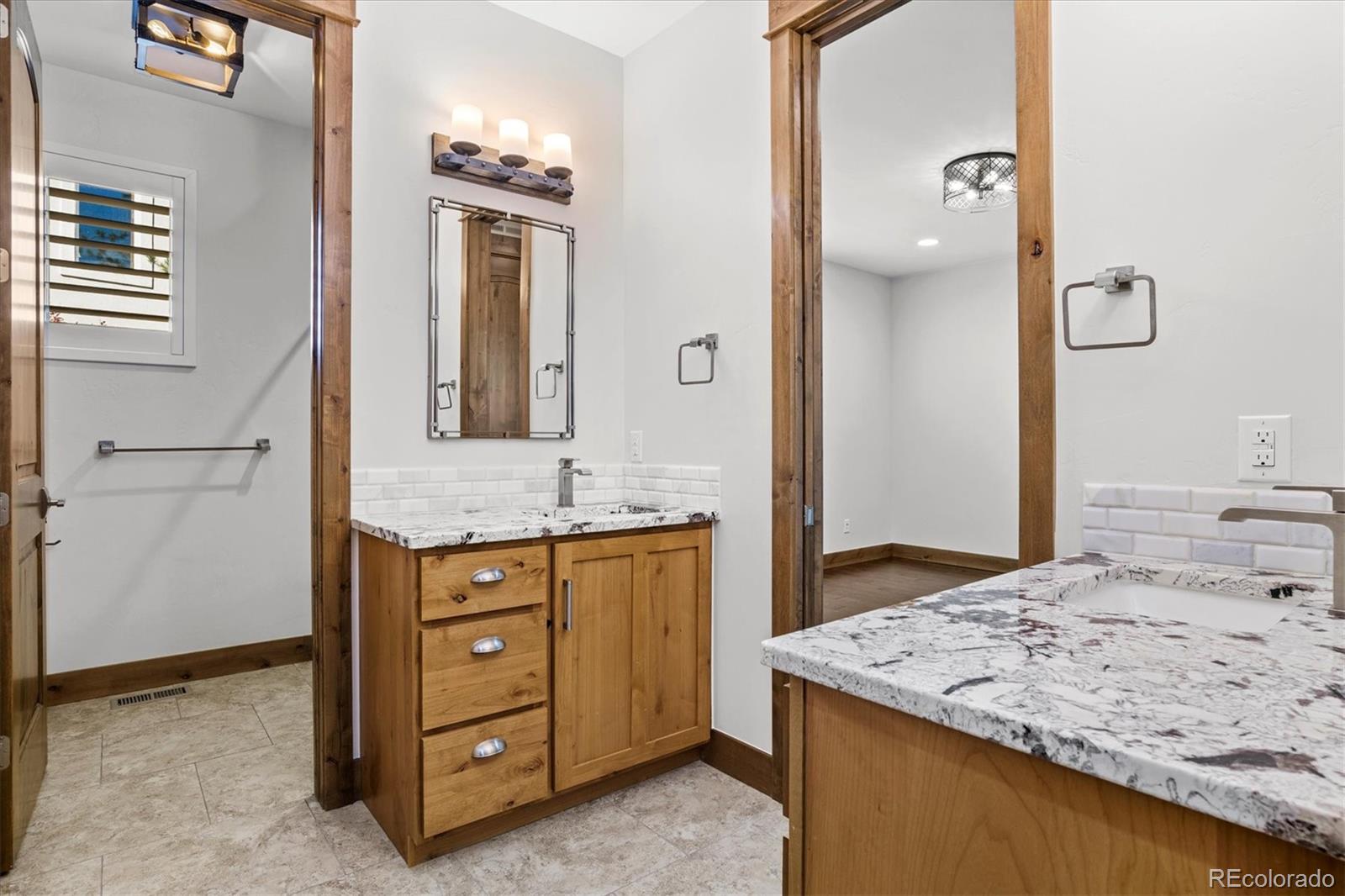 5561 Rim View Place Parker, CO 80134 - Photo 23 of 40 a bathroom with a granite countertop sink and a mirror