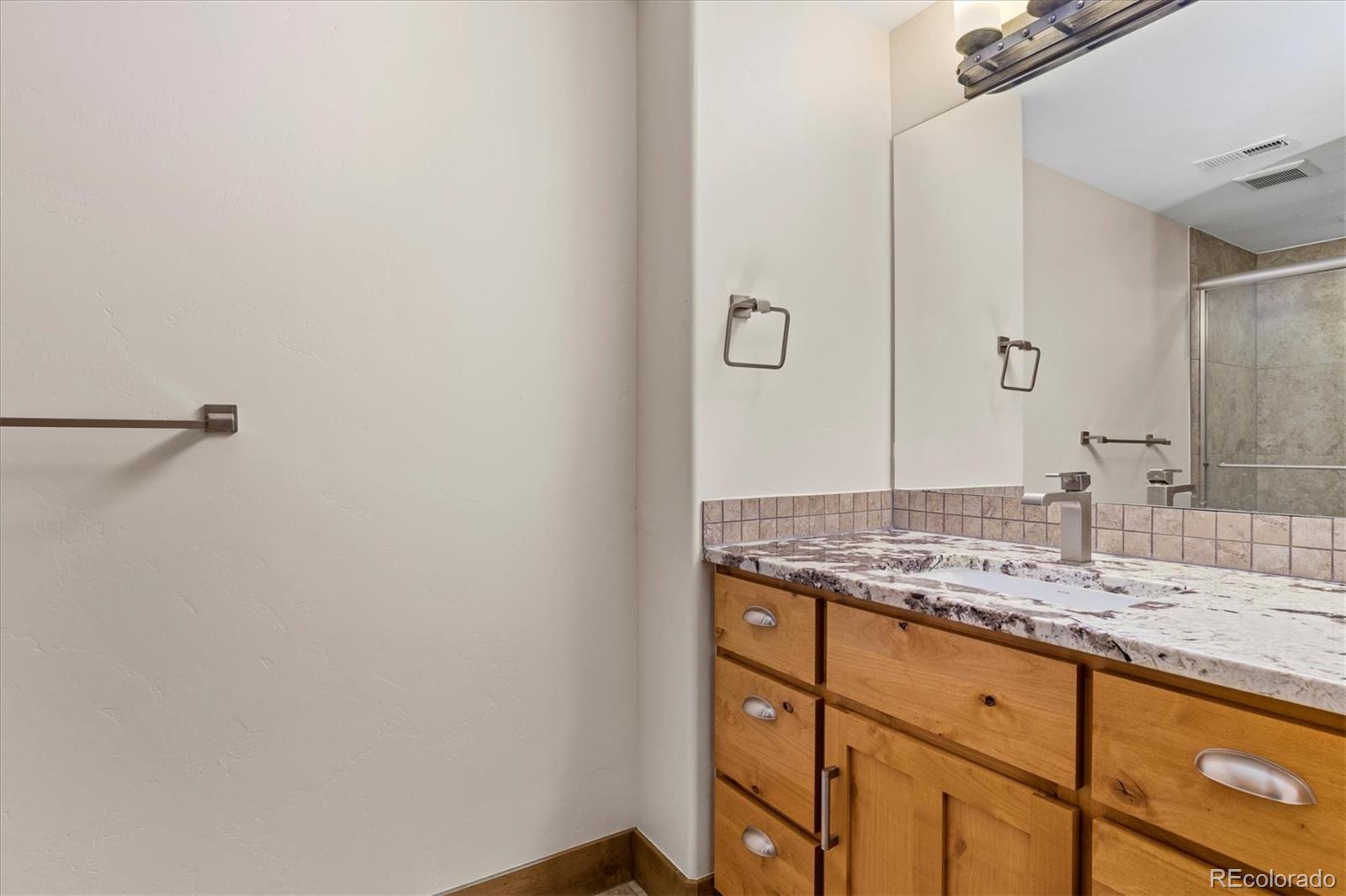 5561 Rim View Place Parker, CO 80134 - Photo 32 of 40 a bathroom with a granite countertop sink and a mirror