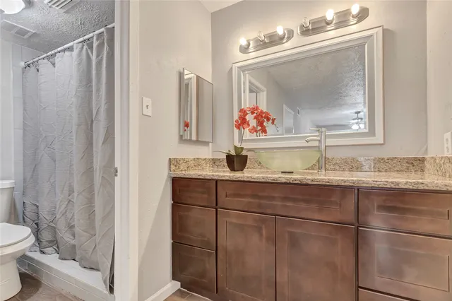 a bathroom with a granite countertop sink a toilet and a mirror