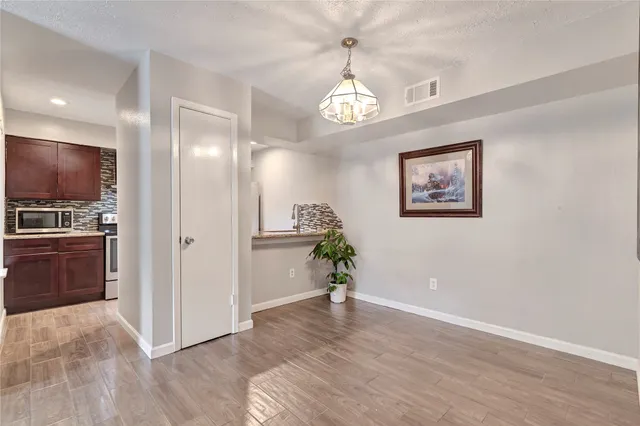 a view of a hallway with wooden floor and a kitchen