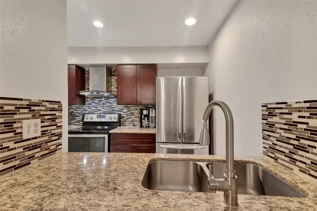 a kitchen with stainless steel appliances granite countertop a stove a sink and a refrigerator