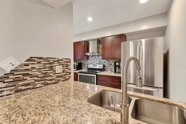 a kitchen with stainless steel appliances kitchen island granite countertop a refrigerator and a stove top oven