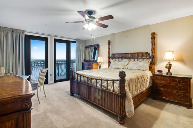 a spacious bedroom with a bed a chandelier and windows