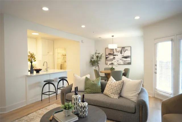 a living room with furniture kitchen view and large windows