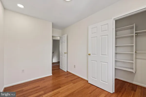 a view of an empty room with wooden floor and closet
