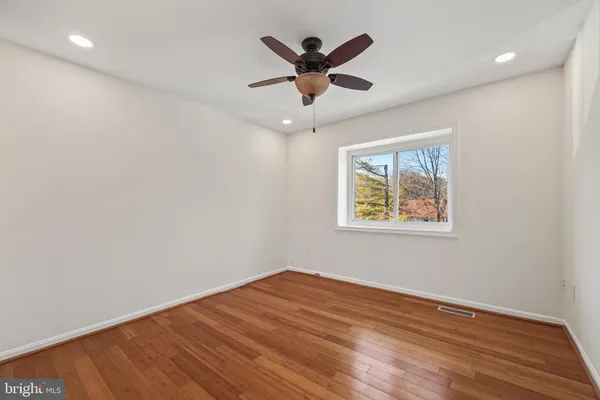 an empty room with wooden floor and ceiling fan