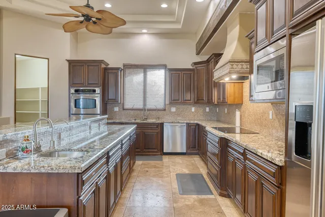 a large kitchen with granite countertop a sink and dishwasher a stove top oven with wooden floor