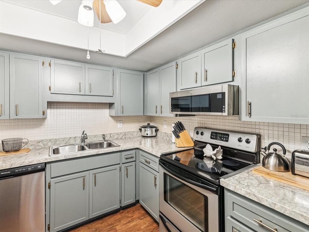 10216 Regal Drive, Unit 409 Largo, FL 33774 - Photo 8 of 42 a kitchen with stainless steel appliances granite countertop a sink stove oven and white cabinets with wooden floor