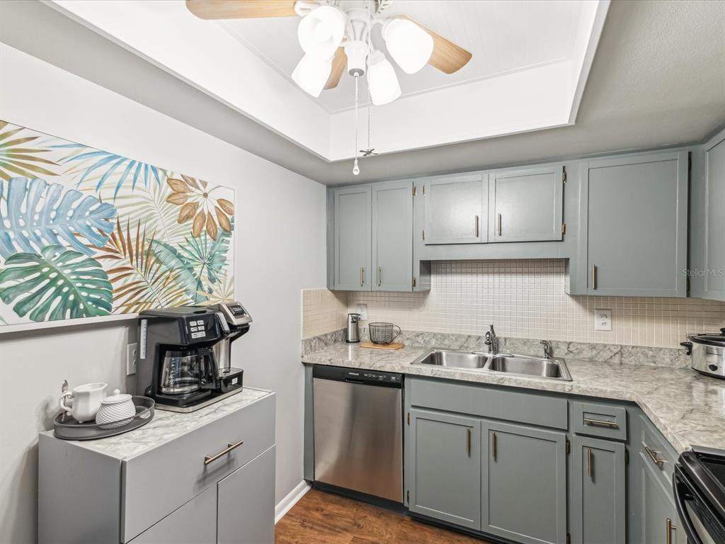 10216 Regal Drive, Unit 409 Largo, FL 33774 - Photo 10 of 42 a kitchen with a sink dishwasher a stove and a refrigerator with wooden floor