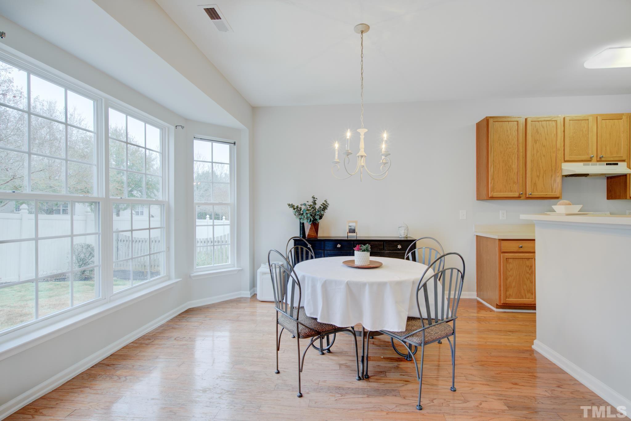 8206 Shadow Stone Court Raleigh, NC 27613 - Photo 15 of 52 a view of a dining room with furniture a chandelier and wooden floor