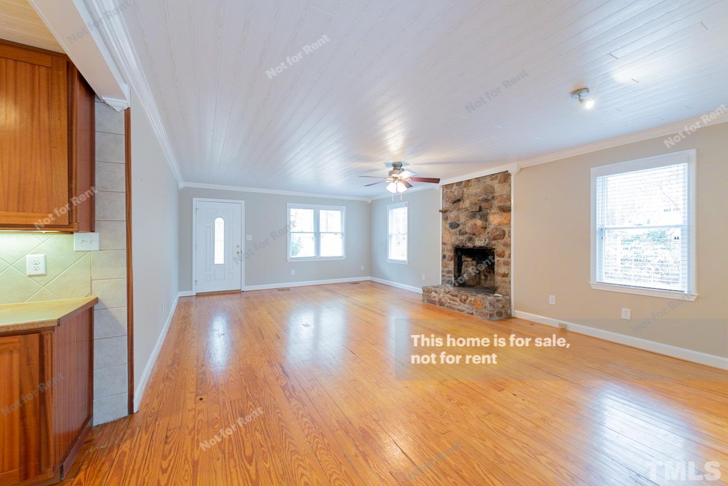12008 Shooting Club Road Raleigh, NC 27613 - Photo 3 of 23 a view of empty room with fireplace and wooden floor