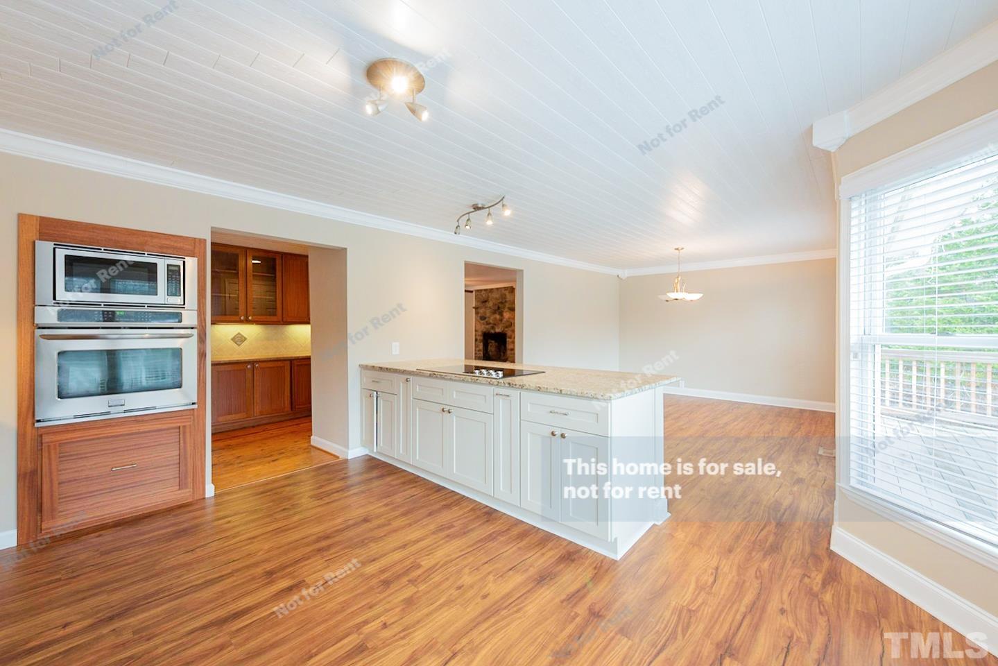 12008 Shooting Club Road Raleigh, NC 27613 - Photo 6 of 23 a large kitchen with kitchen island a sink wooden floor and stainless steel appliances