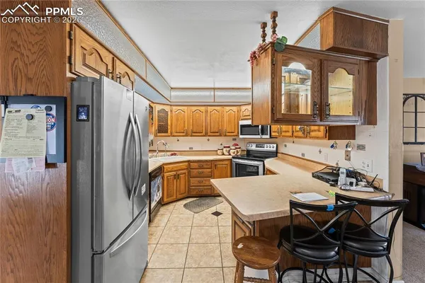 a kitchen with stainless steel appliances a refrigerator a stove a dining table and chairs