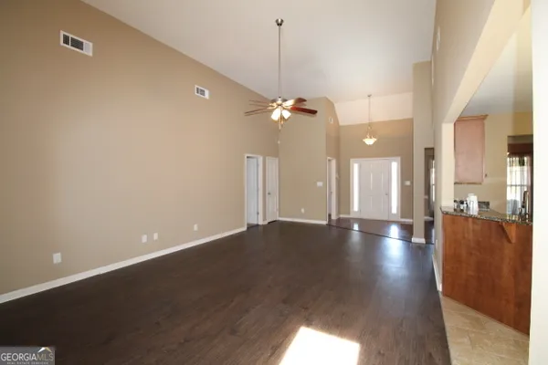 a view of an empty room with a window and wooden floor