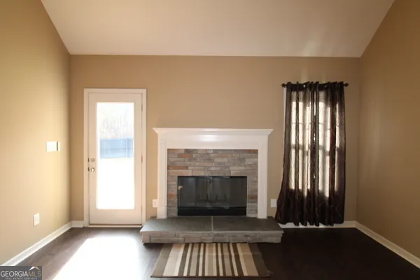 an empty room with wooden floor a fireplace and windows