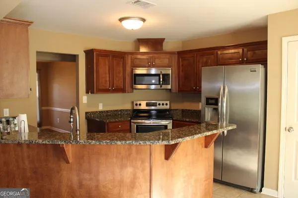 a kitchen with granite countertop a refrigerator and a sink