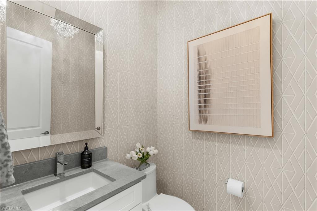 9517 Montelanico Loop Naples, FL 34119 - Photo 24 of 50 a bathroom with a granite countertop sink toilet and mirror