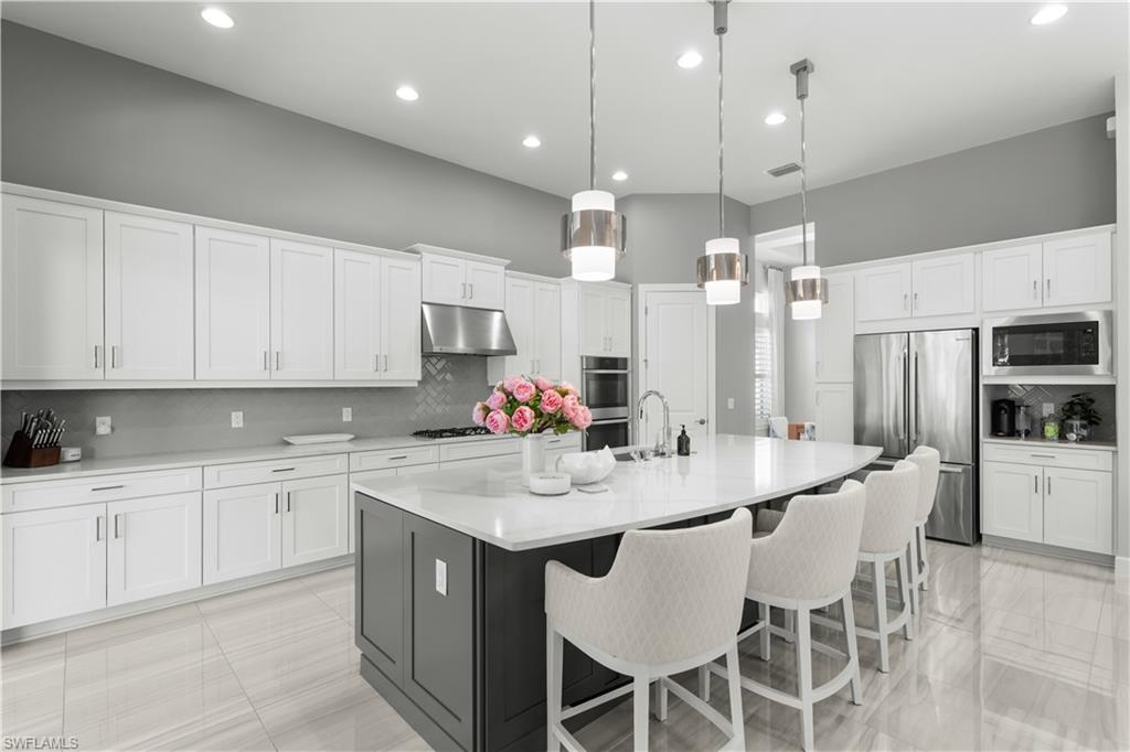 9517 Montelanico Loop Naples, FL 34119 - Photo 7 of 50 a kitchen with stainless steel appliances kitchen island granite countertop a sink and cabinets