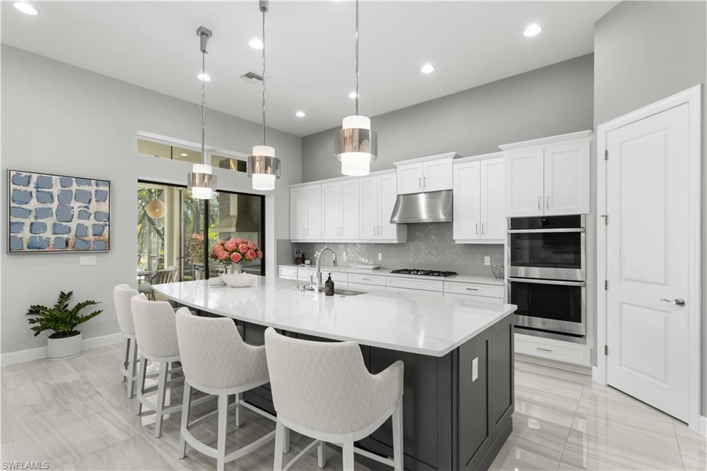 9517 Montelanico Loop Naples, FL 34119 - Photo 8 of 50 a large kitchen with kitchen island granite countertop a table chairs sink and cabinets