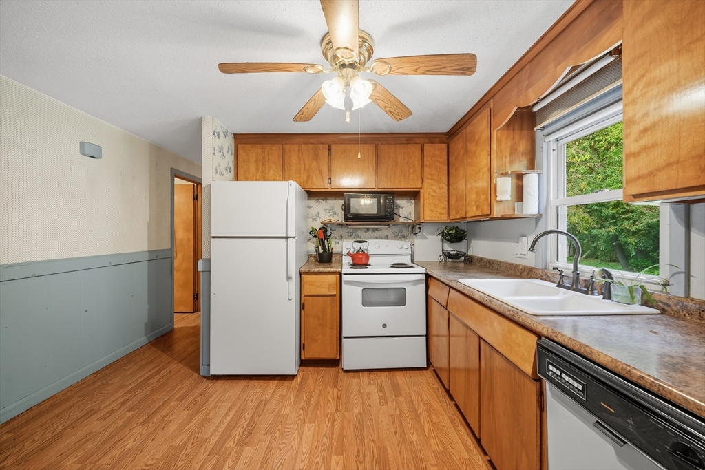 95 Meadowbrook Road Agawam, MA 01001 - Photo 22 of 39 a kitchen with a refrigerator a sink dishwasher a stove and white countertops with wooden floor