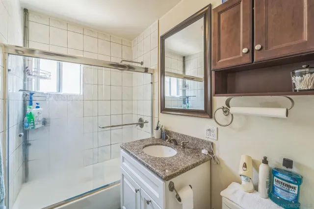 a bathroom with a granite countertop sink a mirror and shower