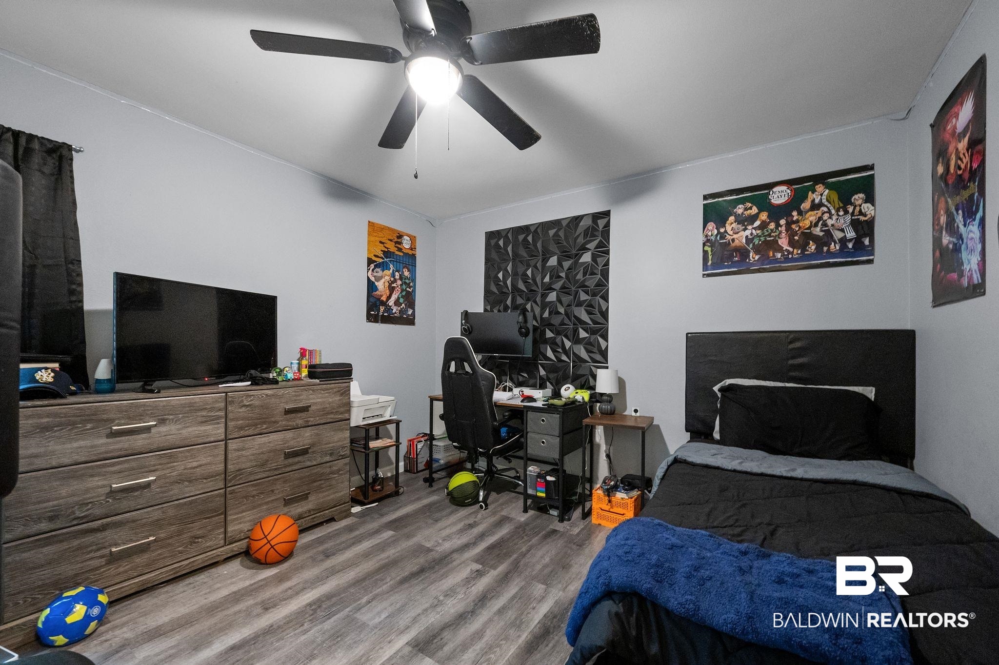 4724 Wicker Way Mobile, AL 36609 - Photo 24 of 36 Bedroom featuring wood-finish flooring, a ceiling fan with integrated lighting, light gray walls, black window coverings, and a geometric wall panel accent