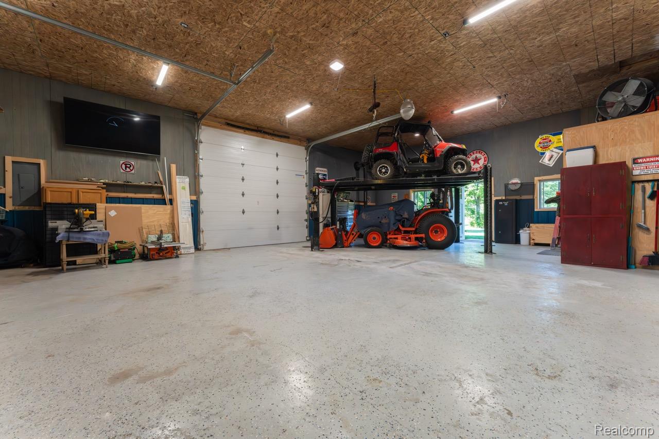 2418 South 41st Road South Cadillac, MI 49601 - Photo 23 of 57 Spacious garage featuring a durable epoxy-coated concrete floor, a large overhead sectional door, and a high-capacity vehicle lift