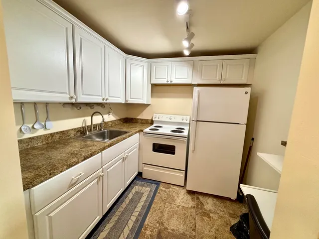 a kitchen with granite countertop white cabinets and a sink