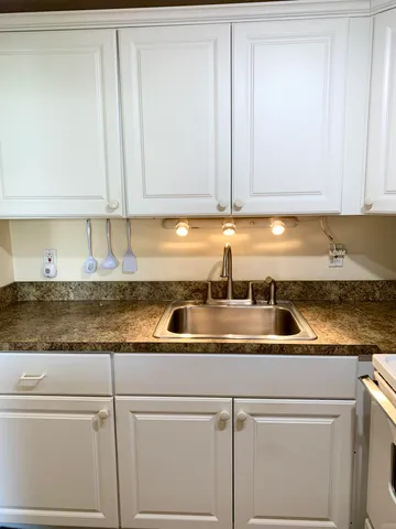 a kitchen with granite countertop white cabinets and white appliances