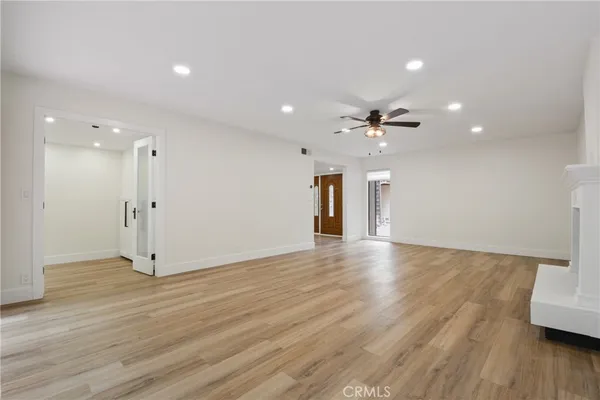 a view of an empty room with wooden floor and a ceiling fan