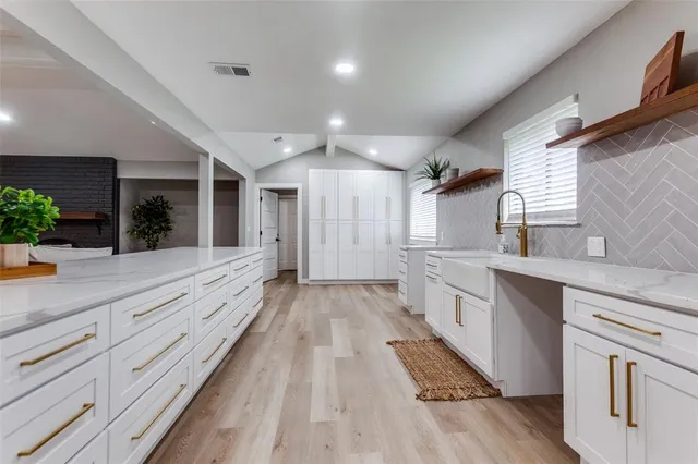 a large kitchen with granite countertop a large counter top space a sink stainless steel appliances and cabinets