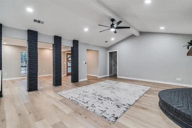 an empty room with wooden floor cabinet and windows