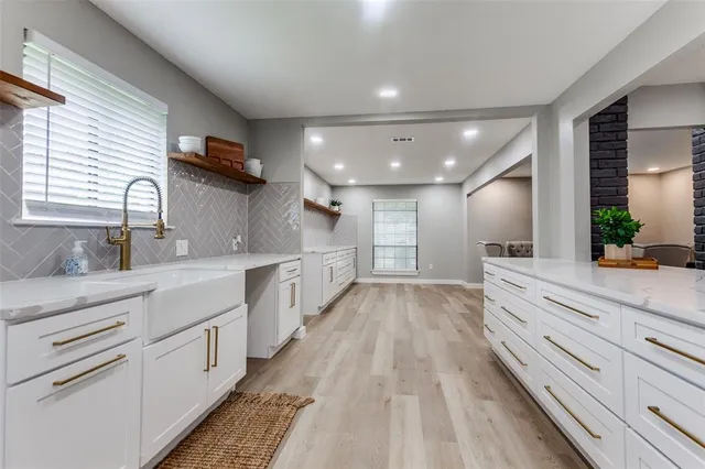 a large white kitchen with granite countertop a large counter top appliances and cabinets