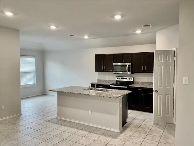 a kitchen with stainless steel appliances granite countertop a stove a sink and a refrigerator