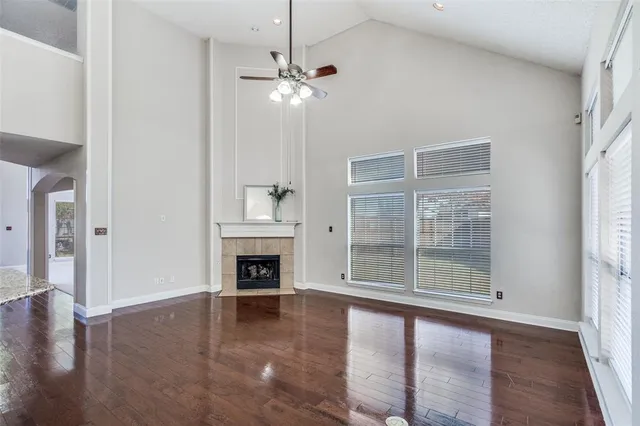 an empty room with wooden floor fireplace and windows