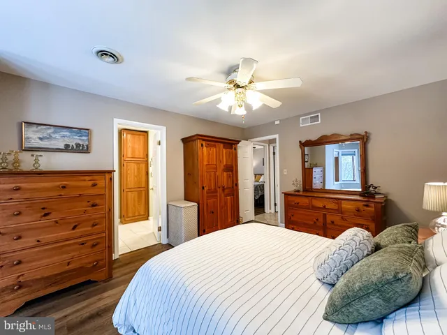 a bedroom with a bed dresser and wooden floor