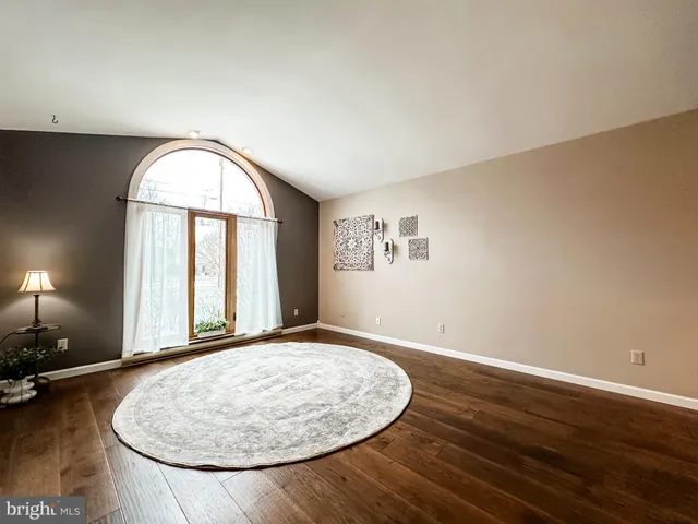 a view of empty room with wooden floor and window