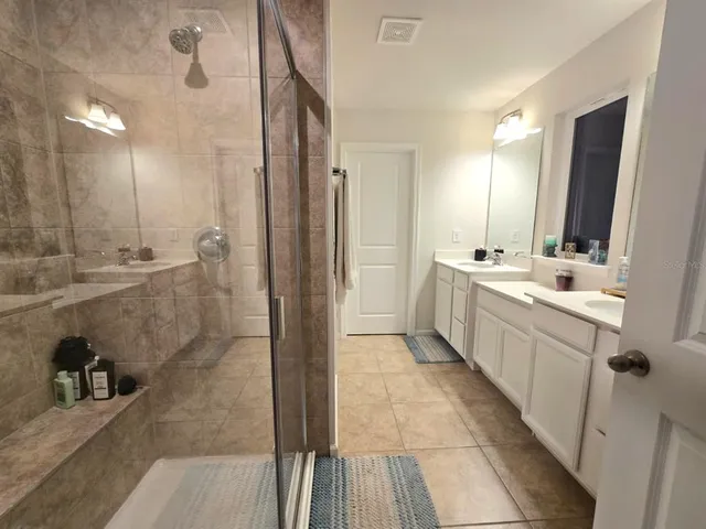 a large bathroom with a double vanity sink a large mirror and shower