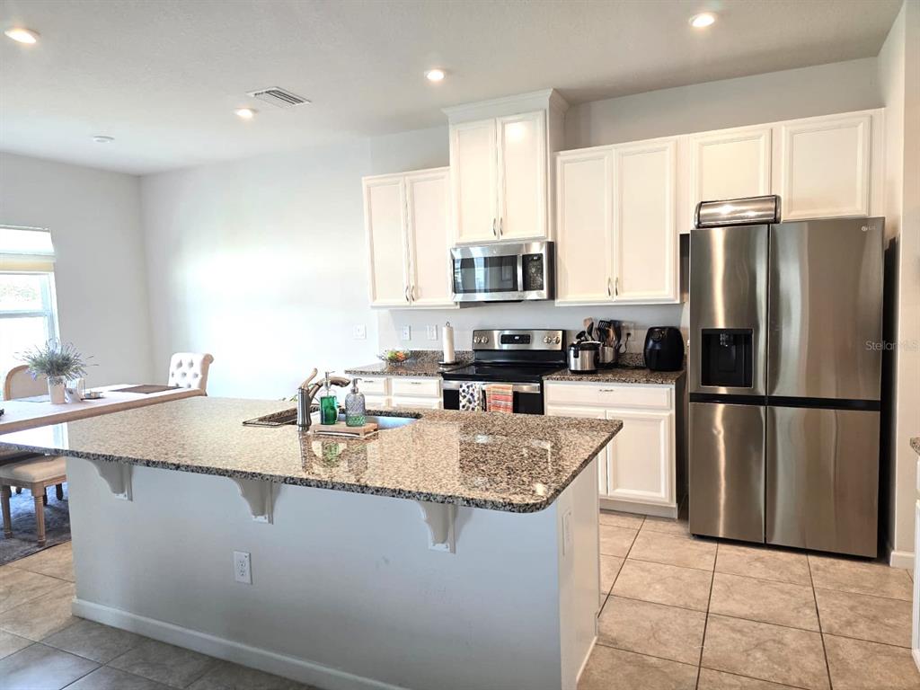 10682 Old Sycamore Loop Land O Lakes, FL 34638 - Photo 3 of 22 a kitchen with stainless steel appliances granite countertop a refrigerator a sink a stove a microwave and island