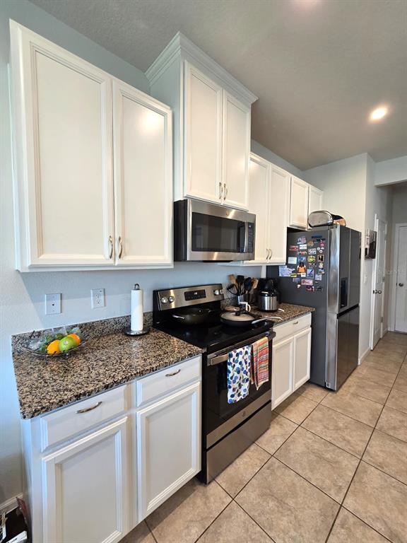 10682 Old Sycamore Loop Land O Lakes, FL 34638 - Photo 4 of 22 a kitchen with stainless steel appliances granite countertop a stove a sink and a microwave
