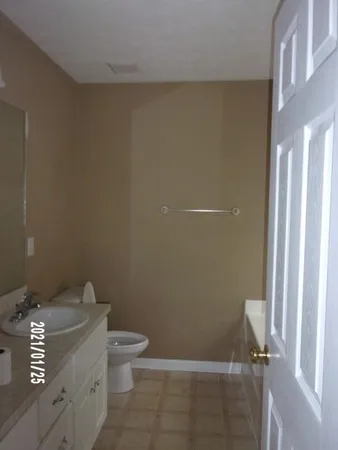 a bathroom with a granite countertop toilet and a sink