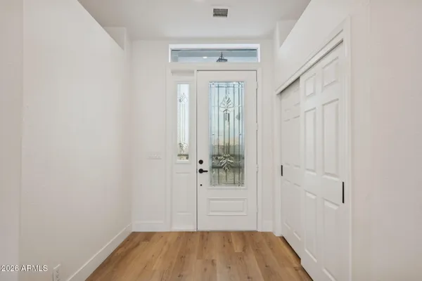 a view of an empty room with wooden floor and a ceiling fan