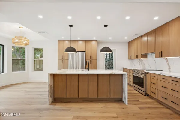 a kitchen with stainless steel appliances granite countertop a sink a stove and a wooden floors