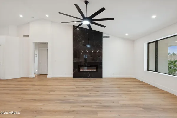 an empty room with wooden floor and ceiling fan