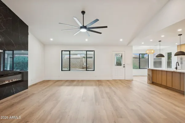 an empty room with wooden floor ceiling fan and windows